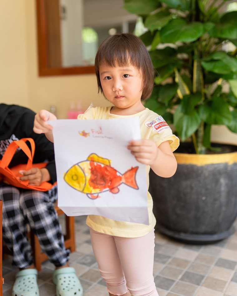 A child at Orange Crest Preschool holding up a painting they have just finished
