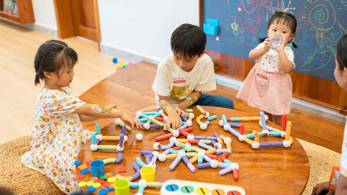 Children working together around a low activity table in a bright classroom at Orange Crest Preschool