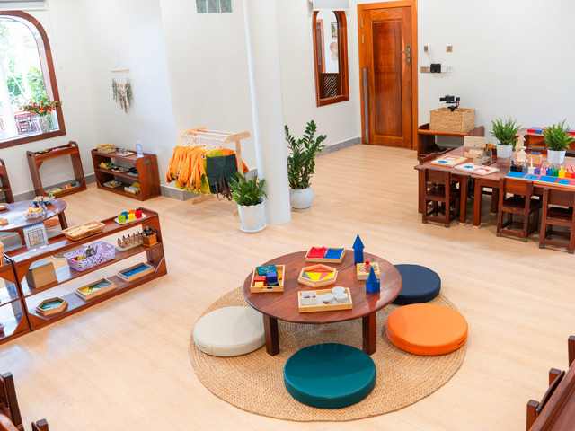 A low round table and floor cushions on a rug in a classroom at Orange Crest Preschool