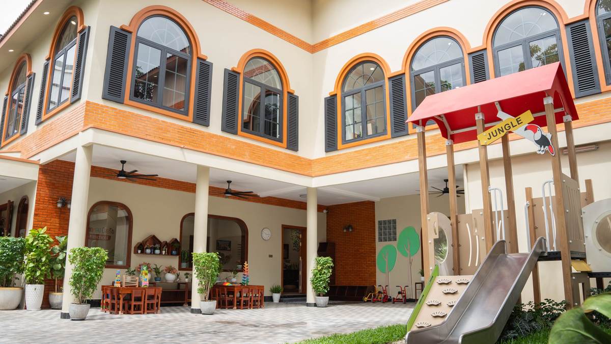 The courtyard at Orange Crest Preschool in Toul Kork, Phnom Penh, with the arched windows of the renovated building and the garden play frame