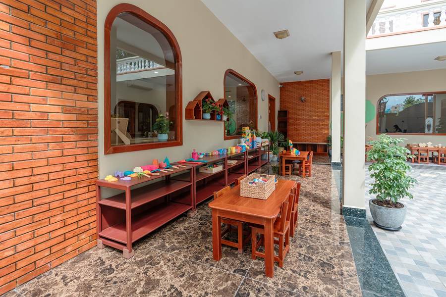 The covered brick arcade at Orange Crest Preschool, with low wooden tables set out along it