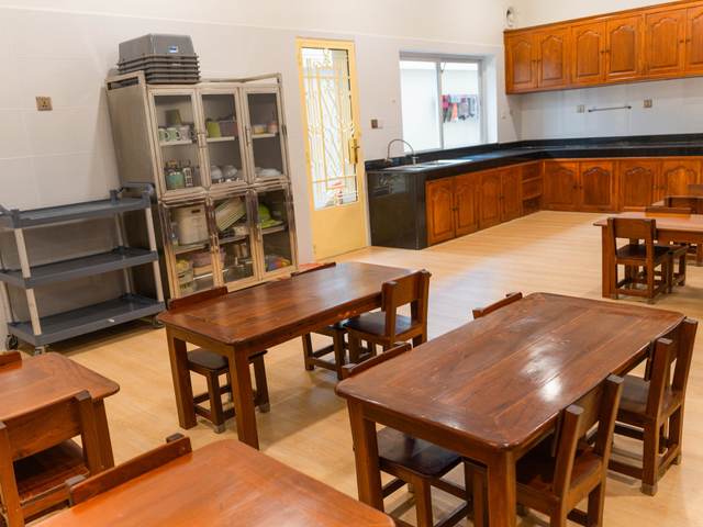 Timber tables and chairs beside the kitchen counter in the dining room at Orange Crest Preschool