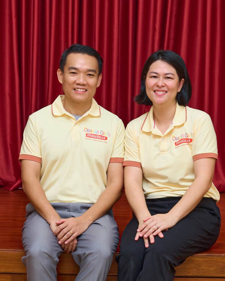 Keath Seng and Judy Zhang, Director and Principal of Orange Crest Preschool, seated together on the stage of the school hall