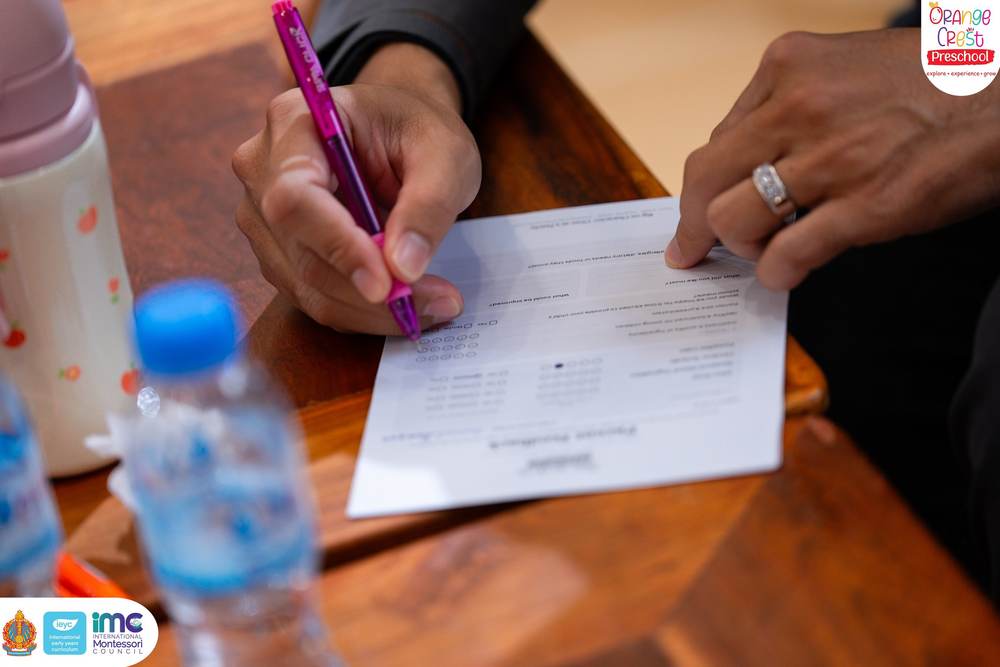 A parent filling in a printed feedback form on a wooden table