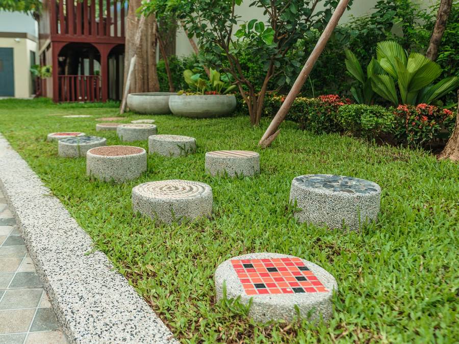 Stepping stones set into the lawn winding between planting beds in the school garden