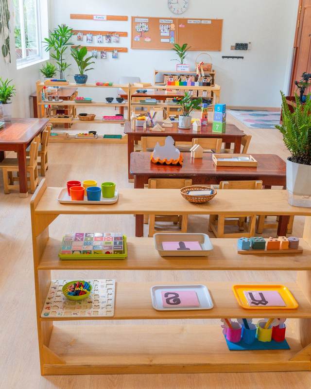 Montessori materials set out on trays on low open timber shelves in a classroom at Orange Crest Preschool