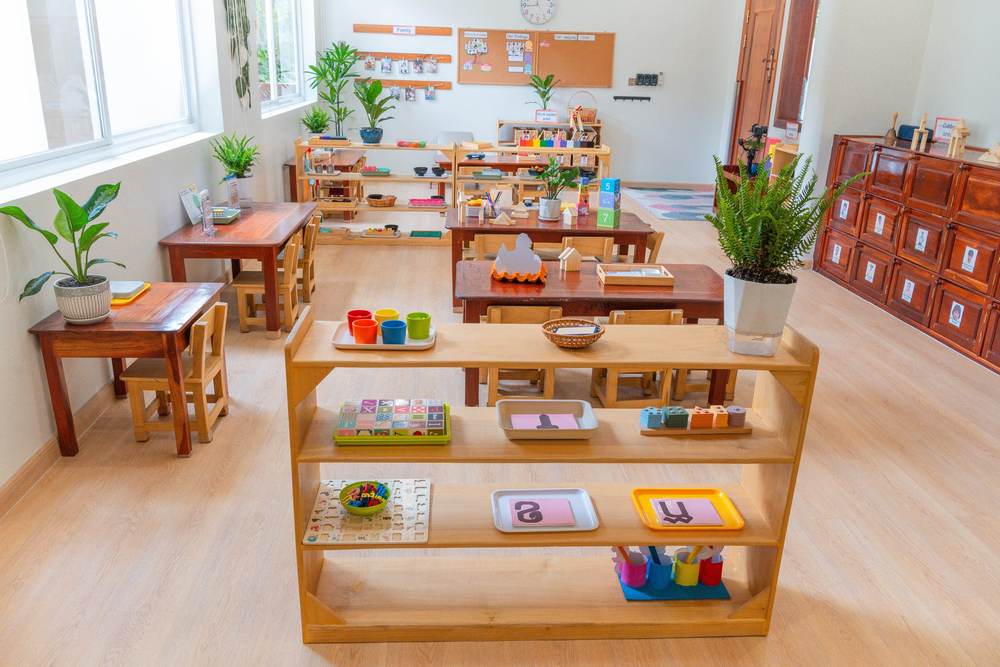 Montessori practical life trays set out on a low wooden shelf in a classroom at Orange Crest Preschool
