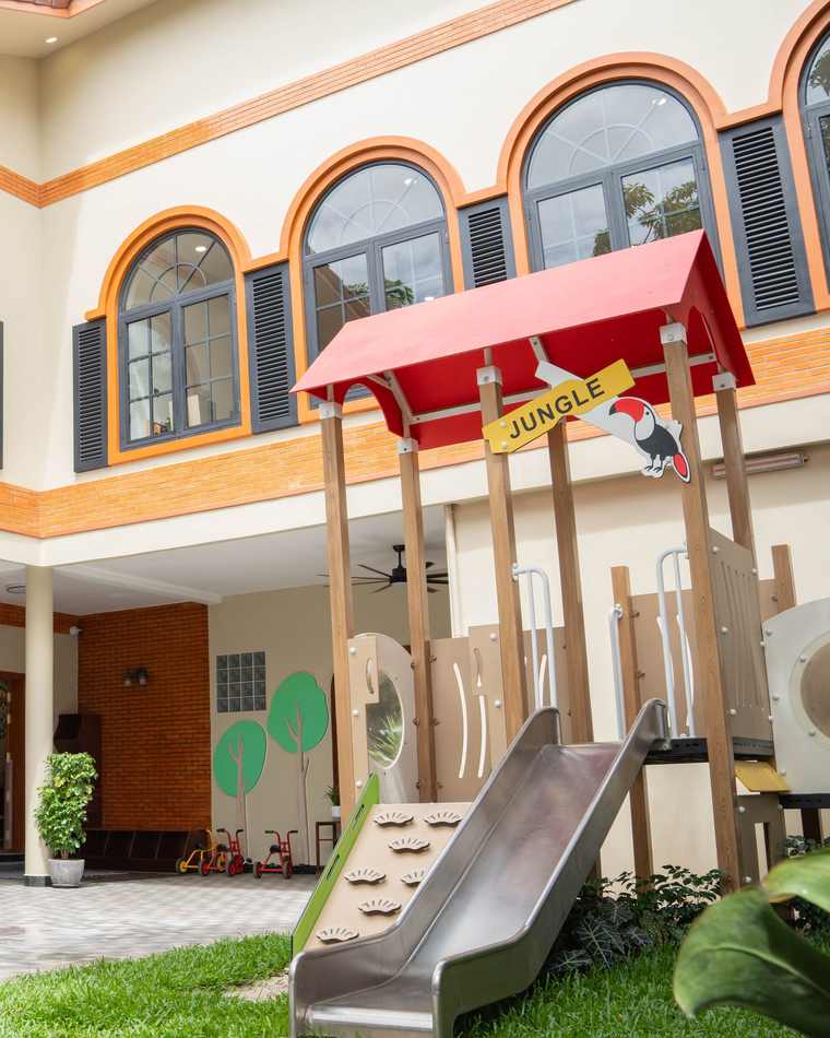 The playhouse and slide in the renovated courtyard of Orange Crest Preschool, beneath two storeys of arched windows