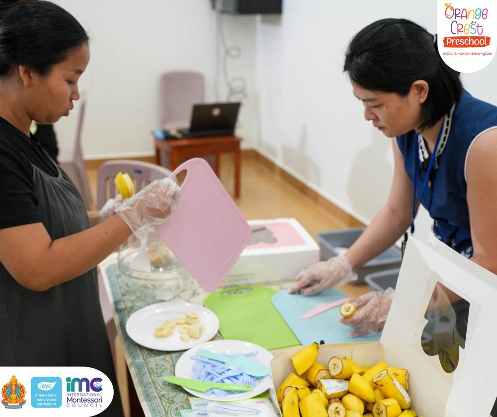 Two members of staff at the front table preparing bananas and rice on trays