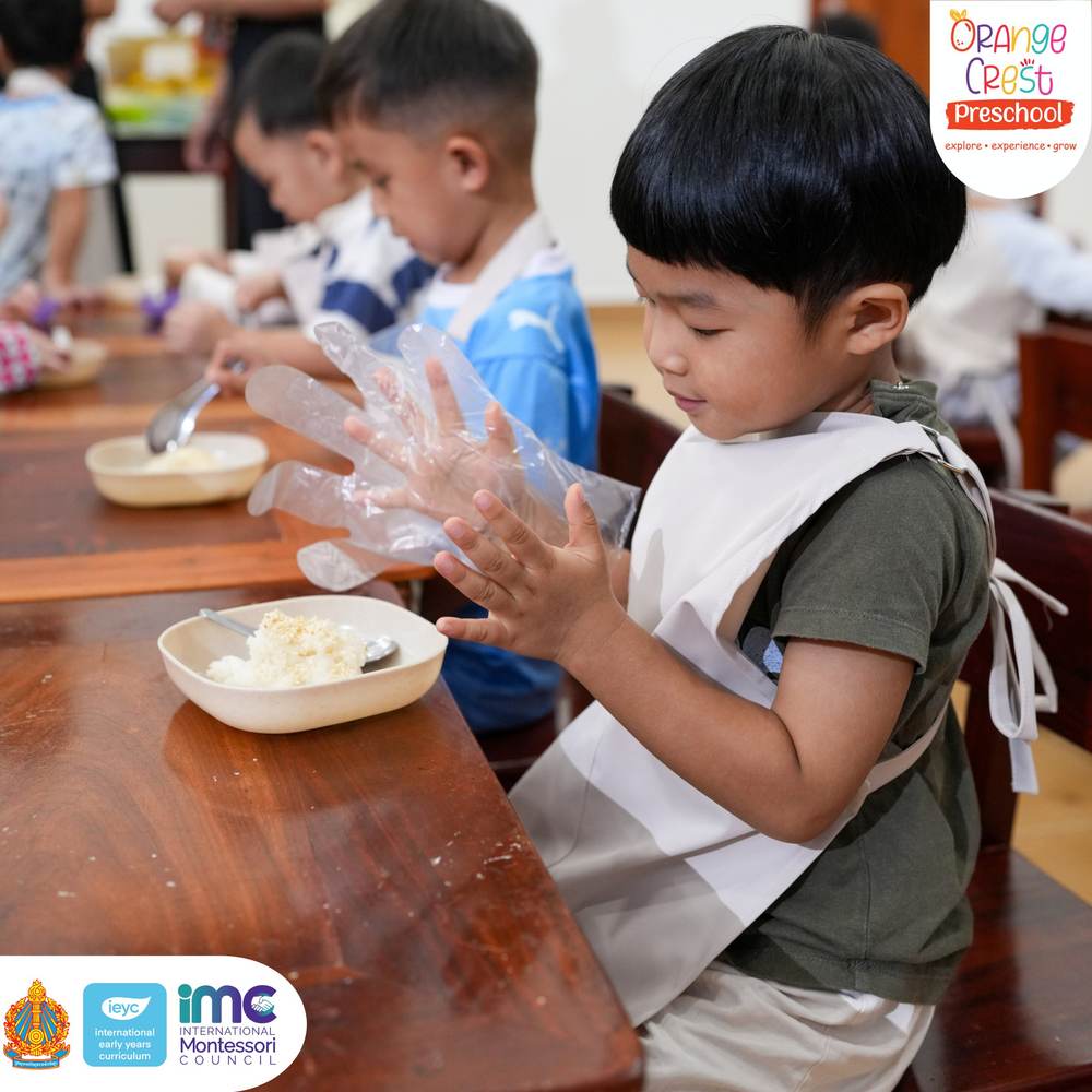 A boy concentrating as he presses a ball of sticky rice together in gloved hands