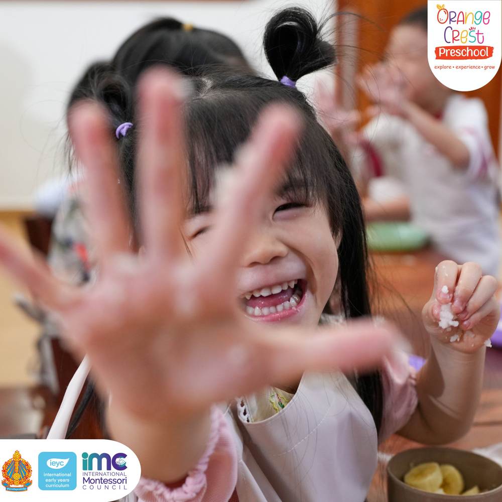A girl laughing with her hands held up to the camera, fingers covered in sticky rice