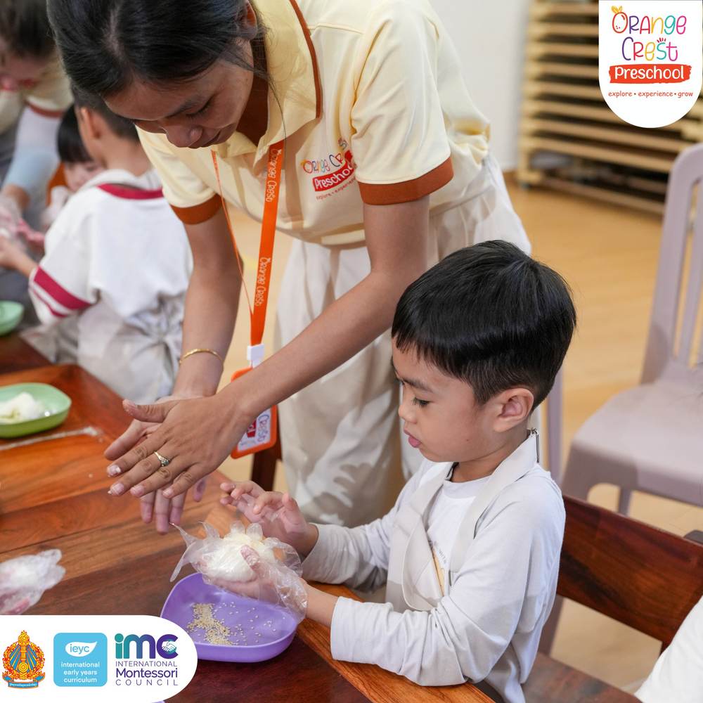A teacher guiding a boy’s gloved hands as he presses rice into a ball