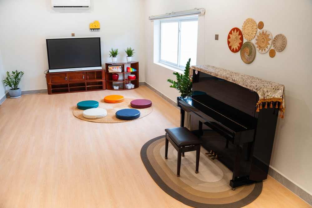 An upright piano, a screen and a ring of floor cushions in a room at Orange Crest Preschool