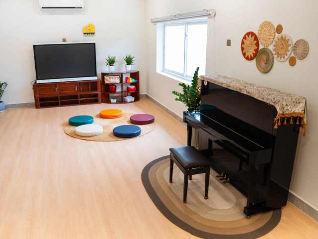 An upright piano, a screen and a ring of floor cushions in a room at Orange Crest Preschool