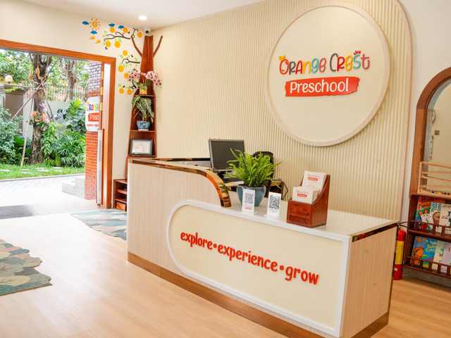 The reception desk at Orange Crest Preschool, with the round school sign on the wall behind it