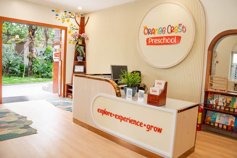 The reception desk at Orange Crest Preschool, with the round school sign on the wall behind it