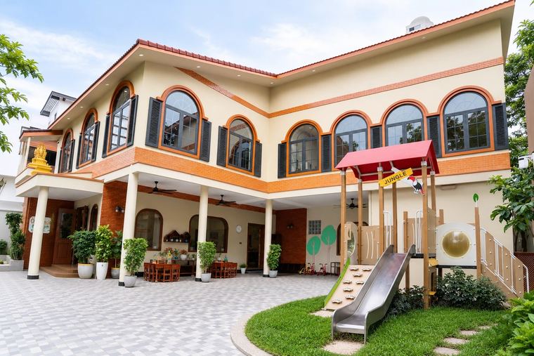 The Orange Crest Preschool building in Toul Kork: two storeys of arched windows above the covered arcade, with the tiled courtyard and the garden play frame