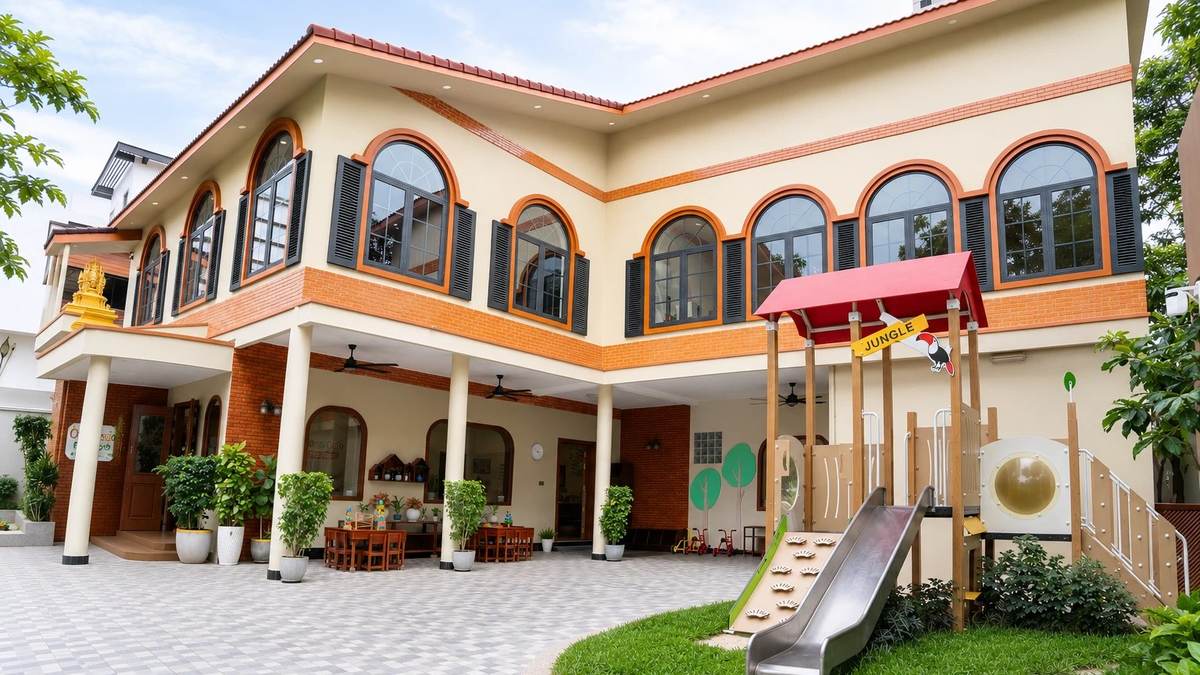 The Orange Crest Preschool building in Toul Kork, Phnom Penh: two storeys of arched windows above the covered arcade, with the tiled courtyard and the garden play frame
